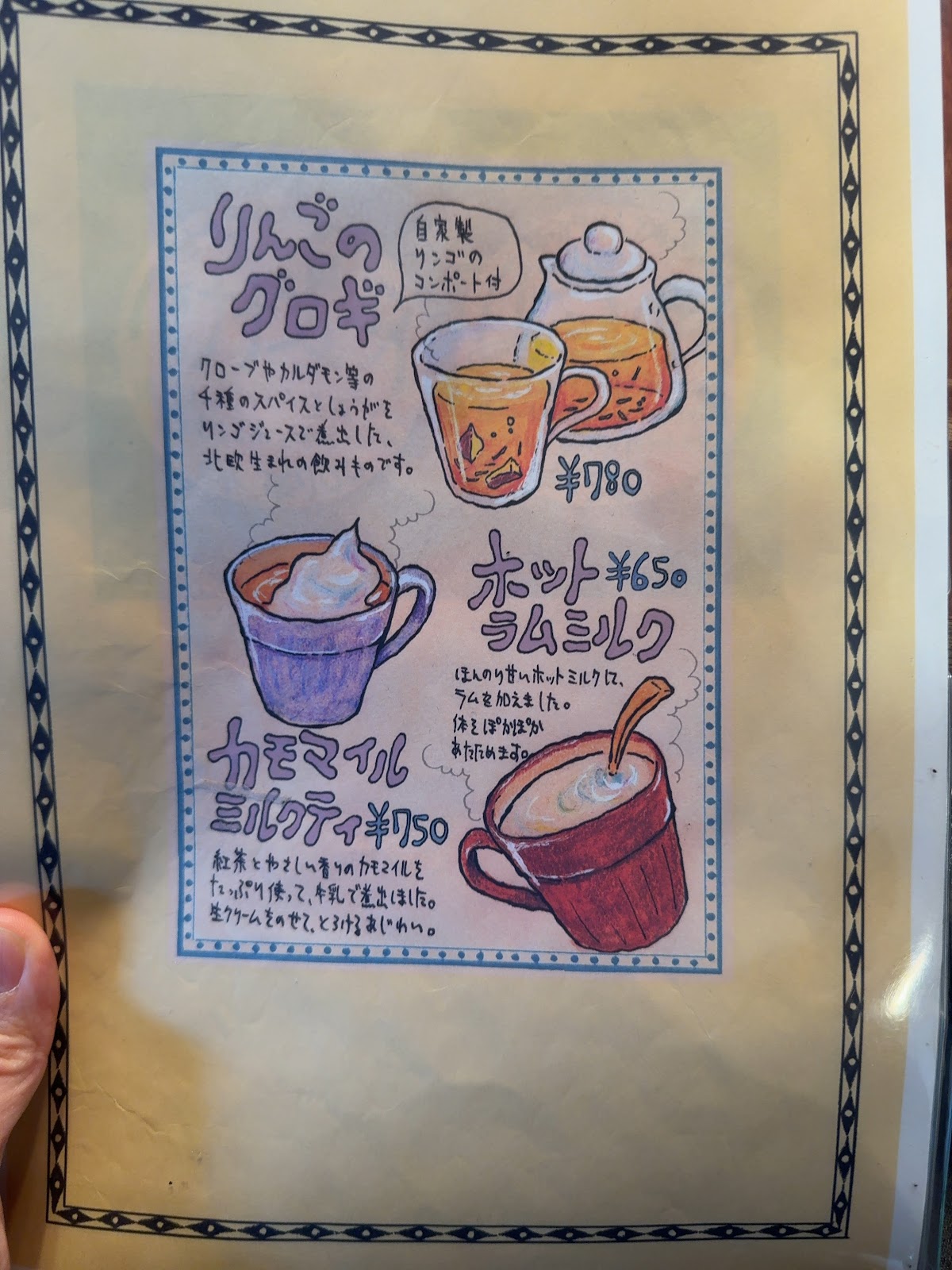 手書きイラスト入りのメニュー表。りんごのグロギ780円、ホットラムミルク650円、カモマイルミルクティ750円が色鉛筆で描かれている